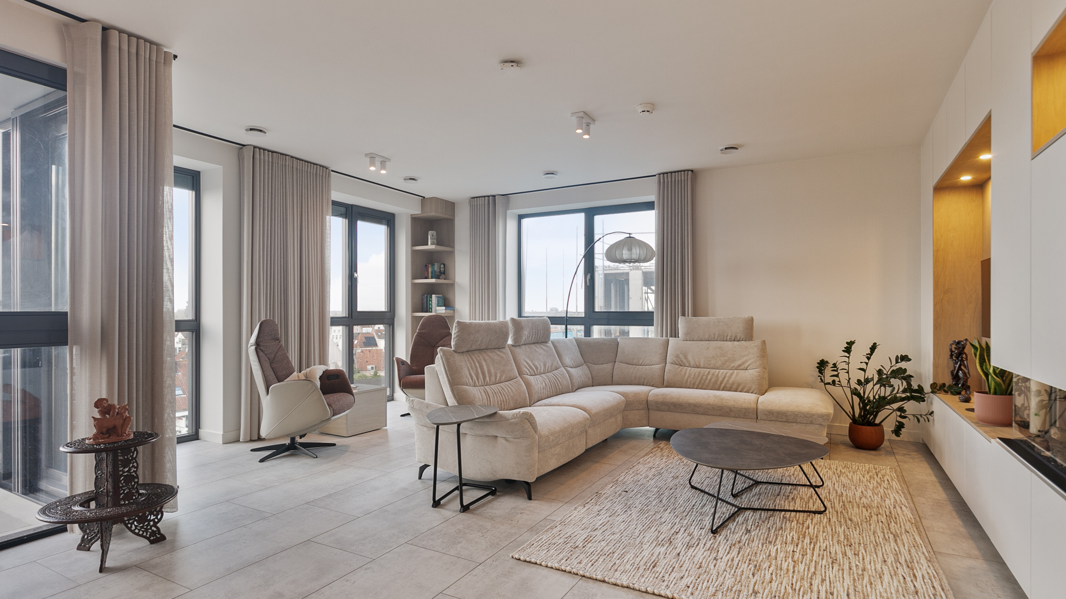 Beige woonkamer met lichte gordijnen en hoekbank.