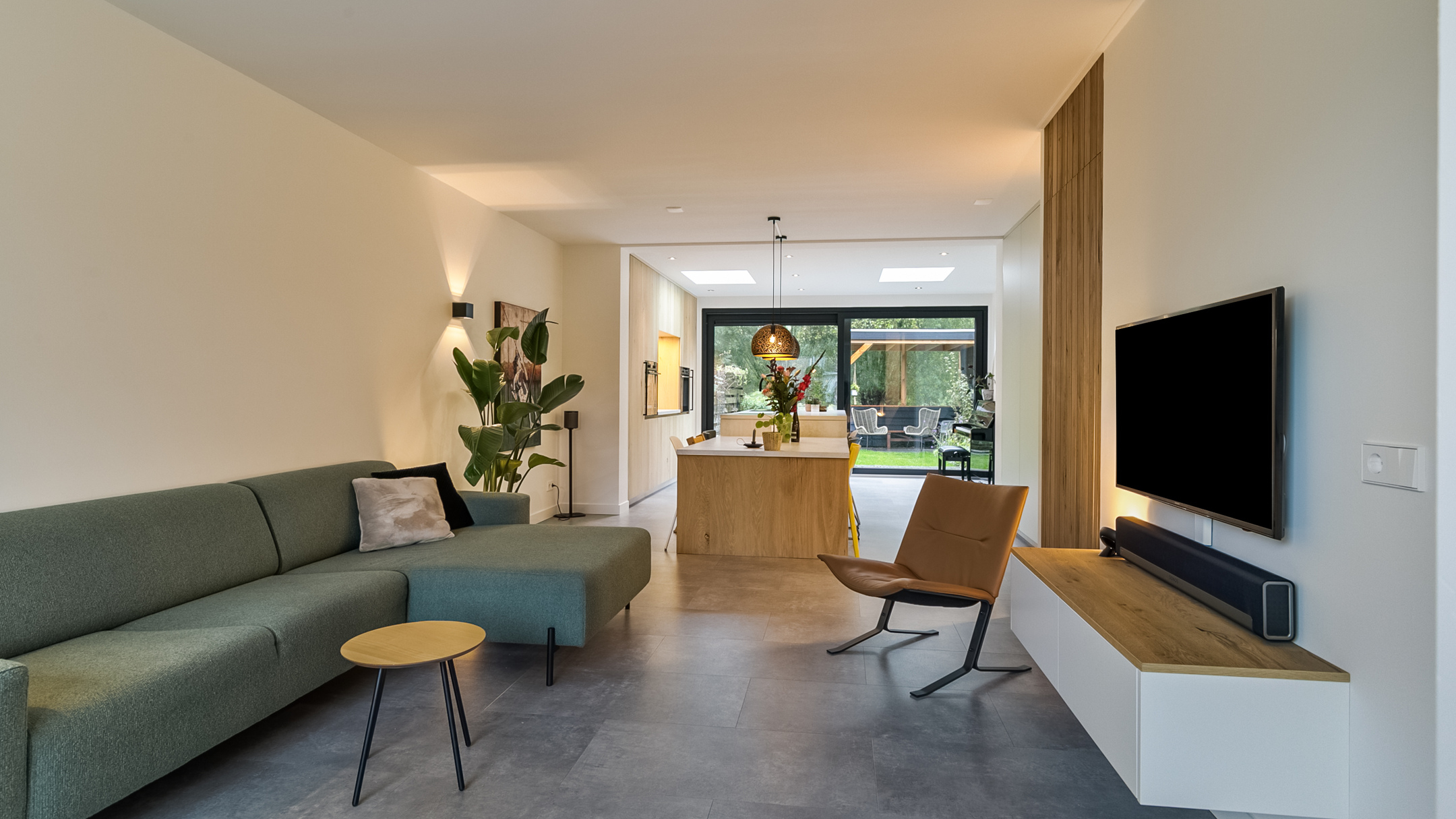 Woonkamer met donkere vloer en groene bank.